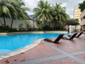 een zwembad met 2 ligstoelen voor een gebouw bij Cozy Studio with Netflix and Pool near Cubao and Greenhills in Manilla