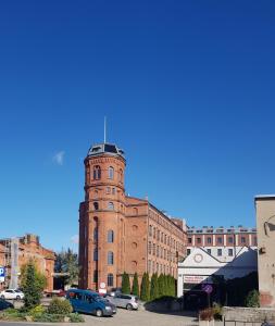 um edifício de tijolos com uma torre de relógio num parque de estacionamento em Studio Mały Rynek em Żyrardów