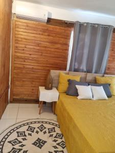1 dormitorio con 1 cama y pared de madera en Le chal'heureux, en Chirongui