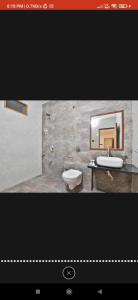 ein Badezimmer mit einem Waschbecken, einem WC und einem Spiegel in der Unterkunft HOTEL SURYAKANT in Rajkot