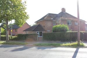 uma casa de tijolos vermelhos com uma rua em frente em Large 7 double bedroom house with large driveway em Earlham