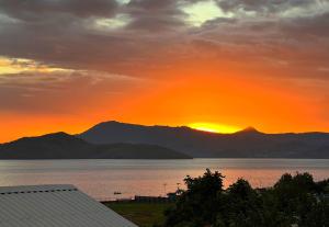 un coucher de soleil sur l'eau avec des montagnes en arrière-plan dans l'établissement Le soundoussia, à Pamandzi