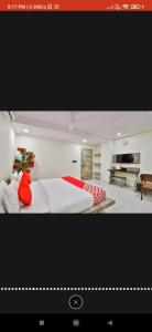 1 dormitorio con cama blanca y almohadas rojas en HOTEL SURYAKANT, en Rajkot