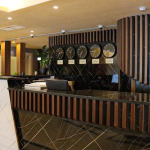 a lobby with a counter with clocks on the wall at Rival Hotel Amman in Amman