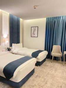 two beds in a hotel room with blue curtains at Rival Hotel Amman in Amman