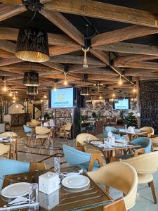 un restaurante con mesas, sillas y TV en Rival Hotel Amman, en Amán