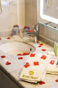 a bathroom sink with a towel with red flowers on it at Rival Hotel Amman in Amman