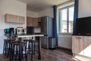 a kitchen with a bar with stools and a tv at LA BÂTISSE l'arbre beige in Le Petit-Abergement