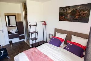 a bedroom with a bed with red and blue pillows at LA BATISSE l'arbre beige in Le Petit-Abergement