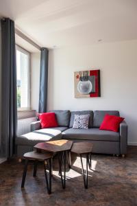 a living room with a gray couch and red pillows at LA BÂTISSE l'arbre beige in Le Petit-Abergement