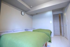 two beds in a room with a clock on the wall at Shinjuku Ryokan Retreat丶Local Tokyo Experience & Short Trips Hub丶walk to Higahsi Shinjuku station YEoL in Tokyo