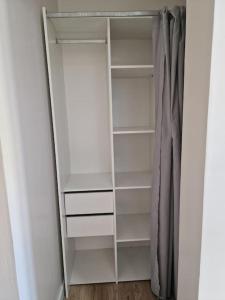 a closet with white shelves and a curtain at L'Owen -10mn Genève-6 Pers-Cosy-Parking privé in Contamine-sur-Arve