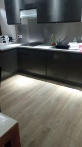 a kitchen with black cabinets and a wooden floor at L'Owen -10mn Genève-6 Pers-Cosy-Parking privé in Contamine-sur-Arve