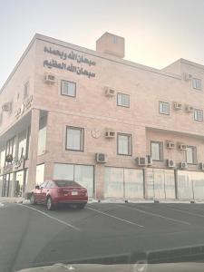 a red car parked in a parking lot in front of a building at سحاب in Yanbu