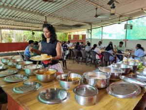 kobieta stojąca przed stołem pełnym jedzenia w obiekcie NS Brothers Farm & Resort w mieście Kolad