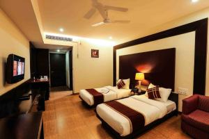 Una habitación de hotel con dos camas y un televisor. en Hotel Cymbal -Sector 31 Gurgaon, en Gurgaon