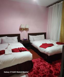 two beds in a hotel room with red sheets at Rabail House in Wadi Musa