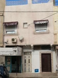 um edifício com duas janelas e uma porta numa rua em Dar manena em Kairouan