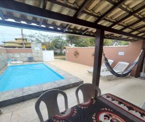 a patio with a swimming pool and a hammock at Meu lugar de Descanso in Cabo Frio