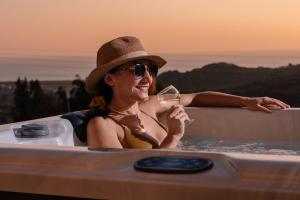 Naxos Aethereal View في كاستراكي ناكشو: امرأة في حوض الاستحمام مع كوب من النبيذ