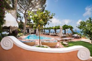 a pool at a resort with chairs and umbrellas at Hotel Punta Tragara in Capri