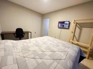 um quarto com uma cama, uma secretária e uma televisão em Espaço BlauHaus próximo a Vila Germânica em Blumenau