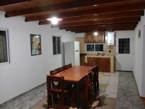 cocina con mesa de madera y nevera blanca en Rock House Embalse en Embalse