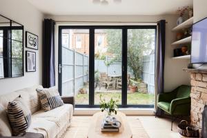 uma sala de estar com um sofá e uma grande janela em The Mitcham Hideout - Lovely 2BDR Flat with Garden em Londres