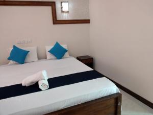 um quarto com uma cama com almofadas azuis e brancas em Gaga Addara Hotel em Matara