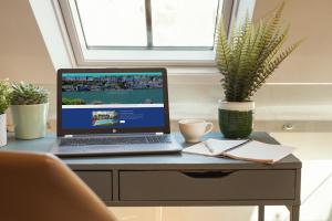 un ordenador portátil sentado en un escritorio con una maceta en 1 Castle Mews, en Dartmouth
