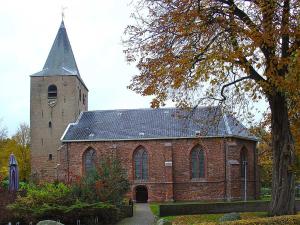 una antigua iglesia de ladrillo con una torre de reloj en Huize Klivia, en Westerbork