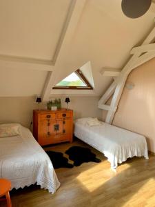 ボジェにあるLe Logis de la Chouetteのベッド2台と窓が備わる屋根裏部屋です。