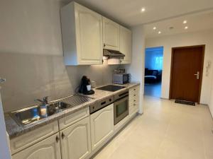 uma cozinha com armários brancos e um lavatório em Vali‘s Apartment One em Dettingen an der Erms