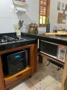 a kitchen with a stove and a microwave at CASA POR TEMPORADA NA SERRA in Ibiapina