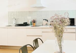 a white kitchen with a table with a vase of flowers at Le Countryside ⸱ Stationnement gratuit ⸱ Fibre in Déols