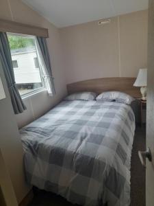 a bedroom with a bed with a blue and white blanket at Arnies Place Beacon Fell in Longridge