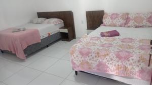 duas camas num quarto com rosa e branco em POUSADINHA LITORAL em Mucuri