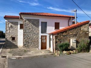 uma pequena casa branca com uma parede de pedra em Casa Luis “el Ferre” em Cudillero