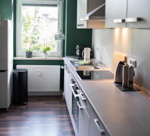 a kitchen with white cabinets and a sink and a window at Zentral Smart Apartment in Zwickau