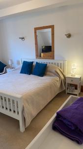 een slaapkamer met een groot wit bed met blauwe kussens bij Beautiful Bexhill Cottage with garden 3 mins walk to beach in Bexhill