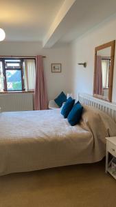a bedroom with a large bed with blue pillows on it at Beautiful Bexhill Cottage with garden 3 mins walk to beach in Bexhill