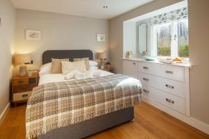 a bedroom with a bed with a dresser and a window at 1 Castle Mews in Dartmouth