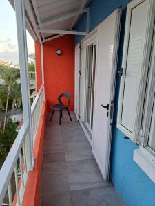 a balcony of a house with a chair and a door at Plein Soleil in Grand-Baie