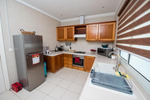 a kitchen with wooden cabinets and a stainless steel refrigerator at Duplex moderne avec vue exceptionnelle sur la mer in Pointe-Noire