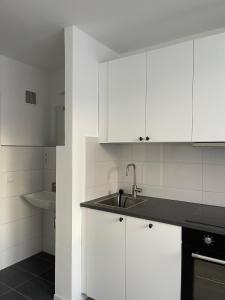 a kitchen with white cabinets and a sink at Schöne Moderne Wohnung am Ring Nr.1 in Cologne