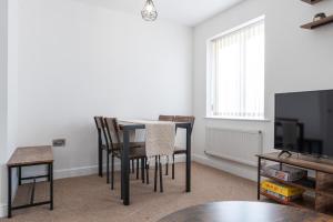 a dining room with a table and chairs and a tv at Parking - Spacious - Smart TV - Self CheckIn - Garden - King in Derby