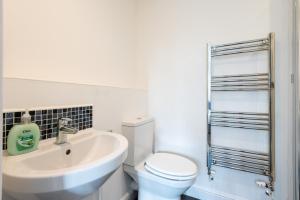 a white bathroom with a sink and a toilet at Parking - Spacious - Smart TV - Self CheckIn - Garden - King in Derby