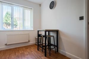 a room with two bar stools and a clock on the wall at Parking - Spacious - Smart TV - Self CheckIn - Garden - King in Derby