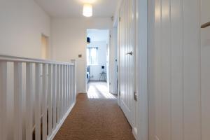 a hallway with white walls and a white staircase at Parking - Spacious - Smart TV - Self CheckIn - Garden - King in Derby