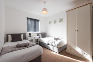 a bedroom with two beds and a table with a chair at A beautiful serviced home with parking and garden, Derby in Derby